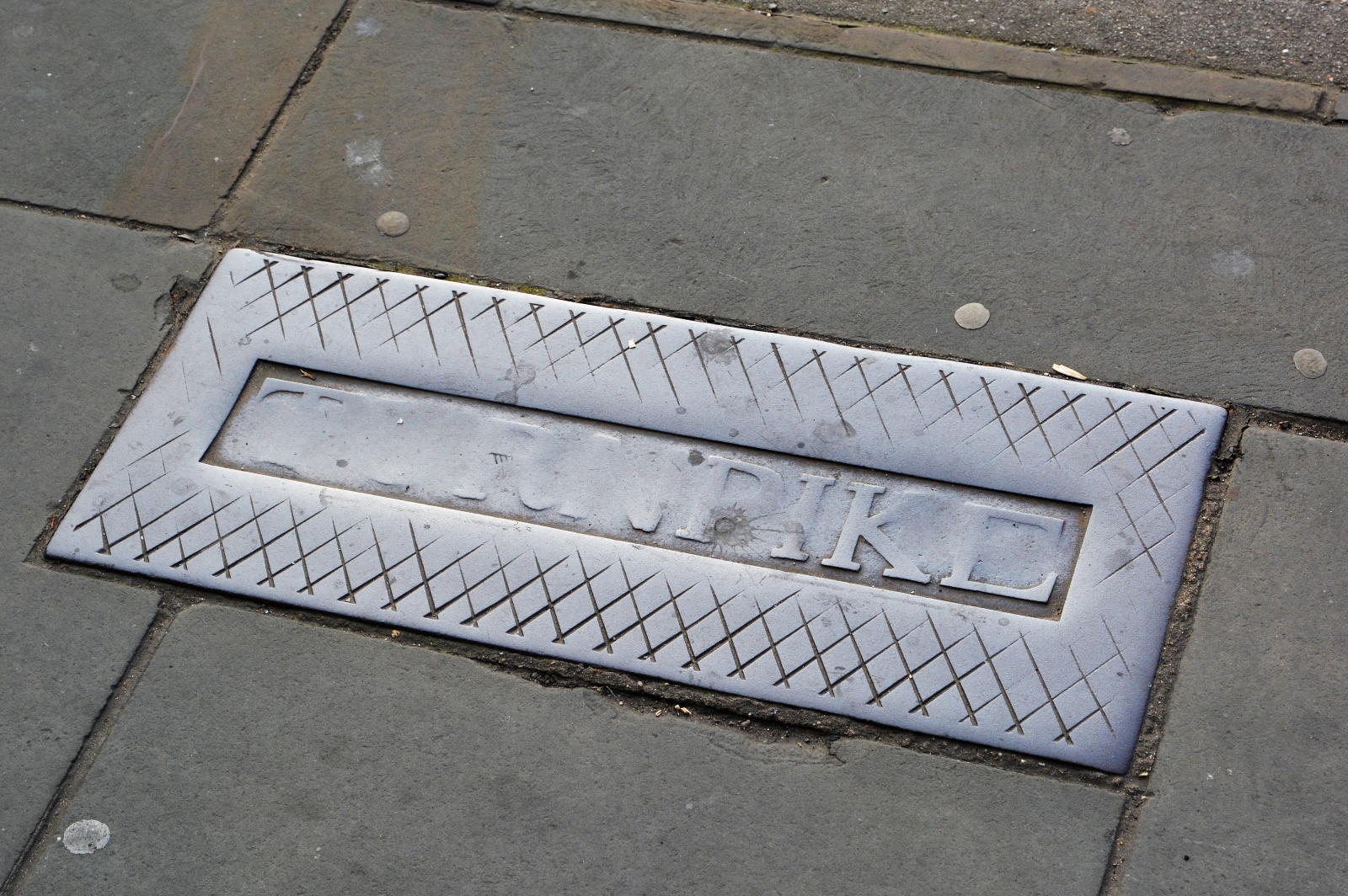A turnpike marker in the pavement outside Cammack’s furniture store